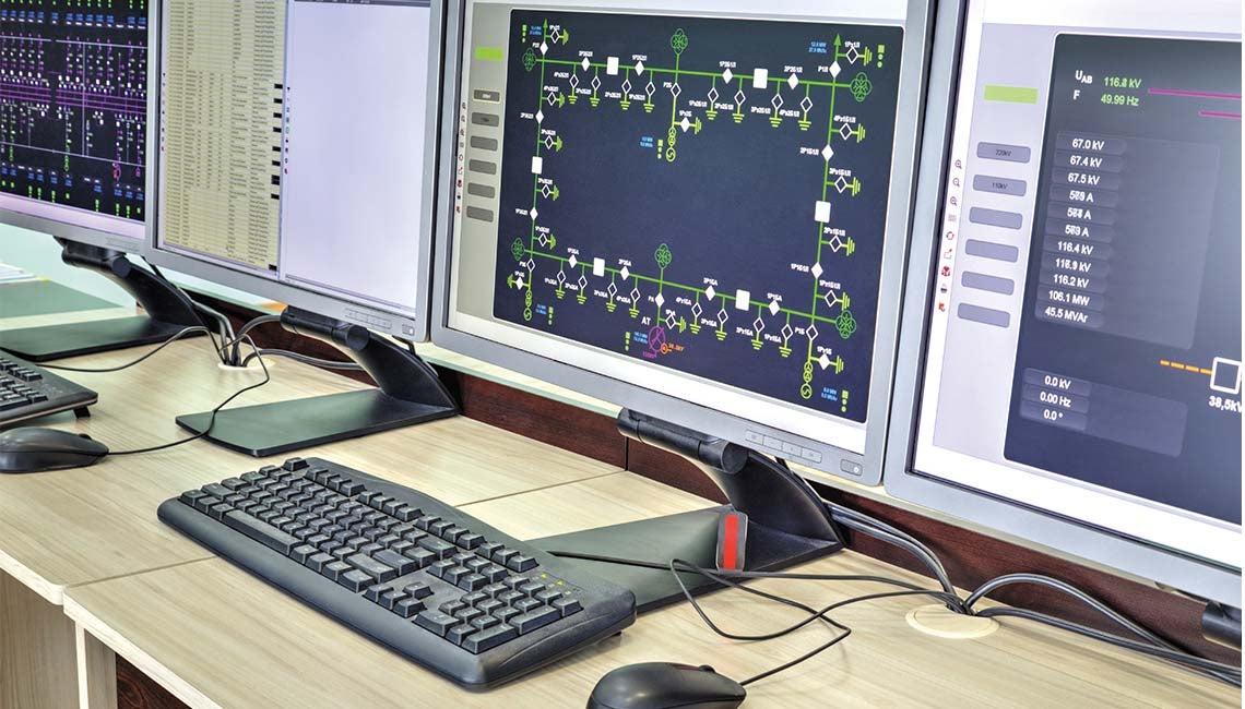 Computer monitors on desk with screens showing electric industry programs.