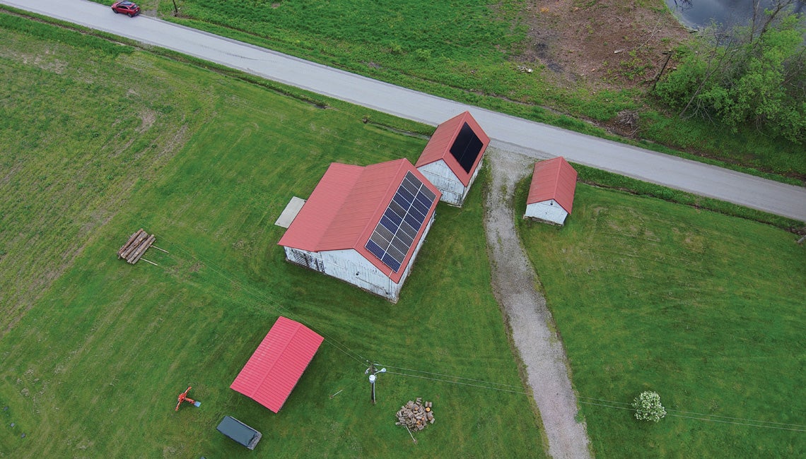 An overhead shot of barns with solar panels on the roofs.