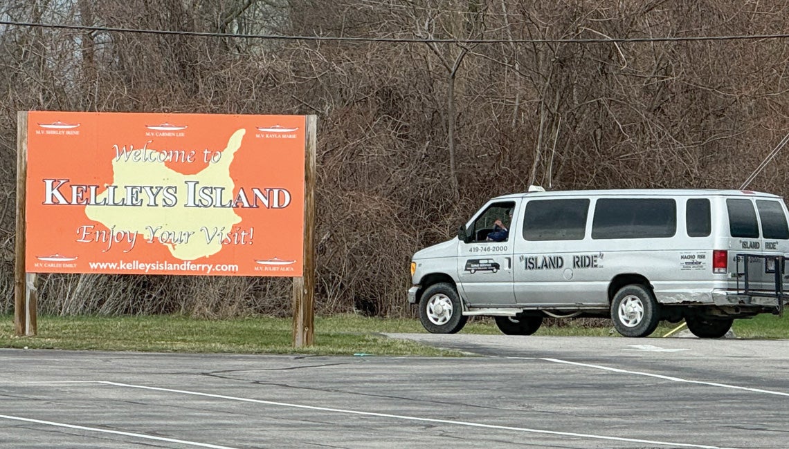 A rideshare van beside a sign