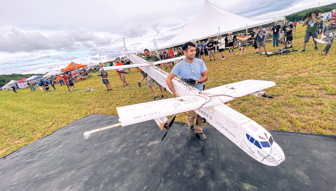 Two men carrying a massive 3-D printed airplane