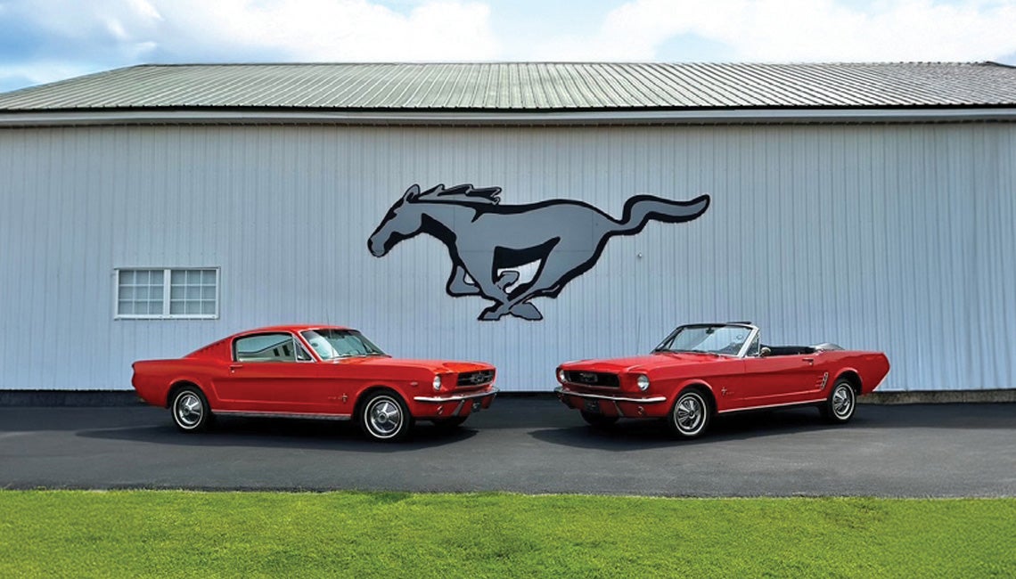 Two historic Mustangs parked in front of a building