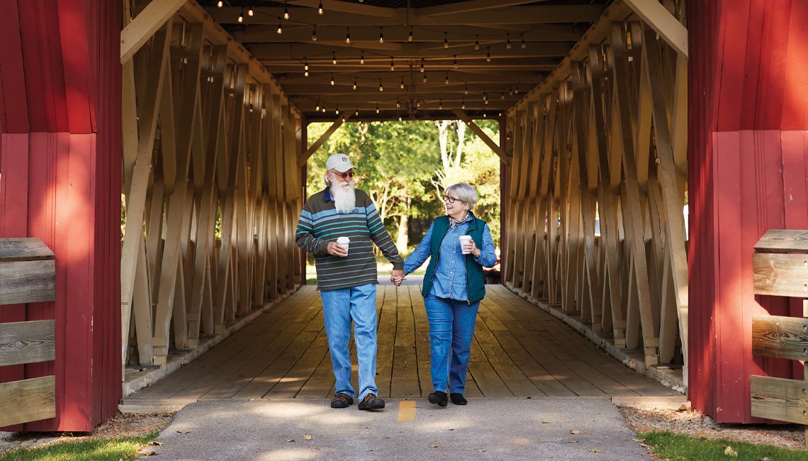 A couple walking hand-in-hand through a covered bridge
