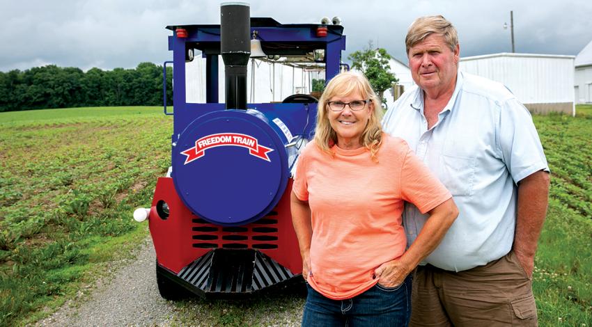 Carol and Tom Schlueter smile together in front of their Freedom Train. 