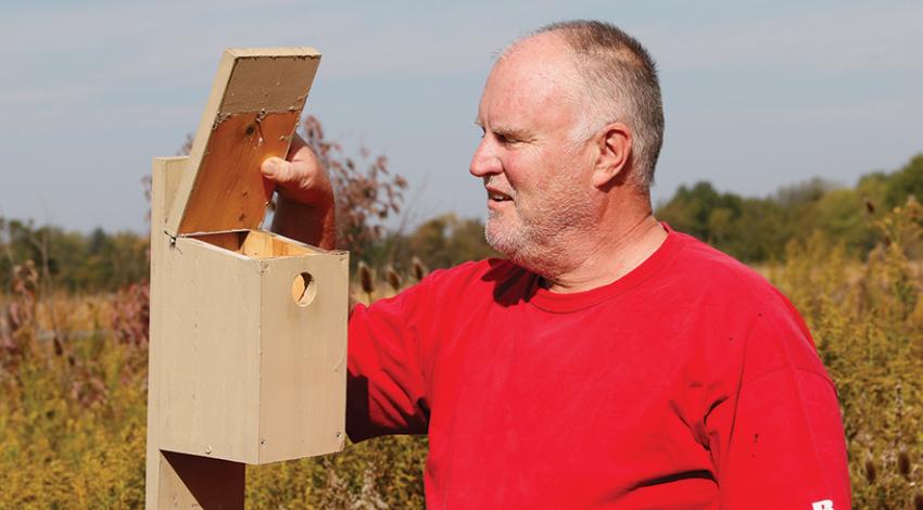 Joe Bodis opens the top of a birdhouse to examine the insides.