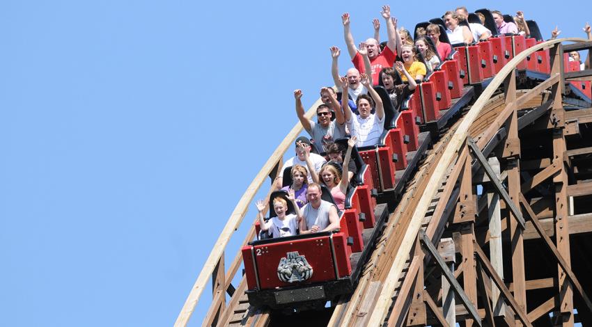 Riders of The Beast put their hands in the air as they start to descend a hill on the coaster