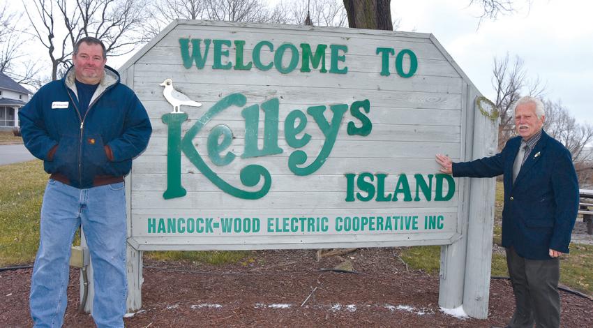 David Ervin and Knute Lahrs pose for a picture beside the sign for Kelleys Island.