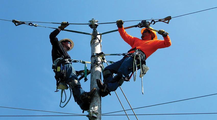 Two lineworkers work on a power line.