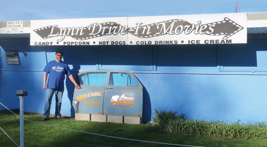 Rich Reding stands beside the sign for Lynn Auto Theatre.