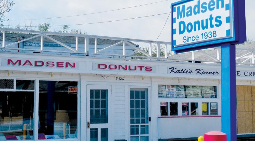 A picture of the outside of Madsen Donuts, featuring a large sign highlighting their history since 1938.