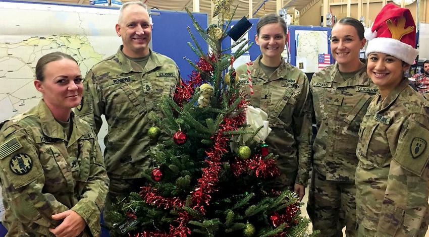 American Troops smile around a Christmas tree.