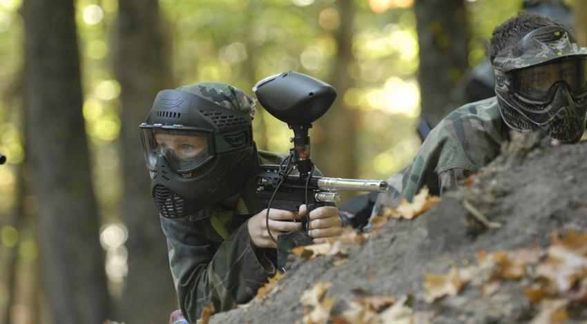 Two paintballers peer over a rock.