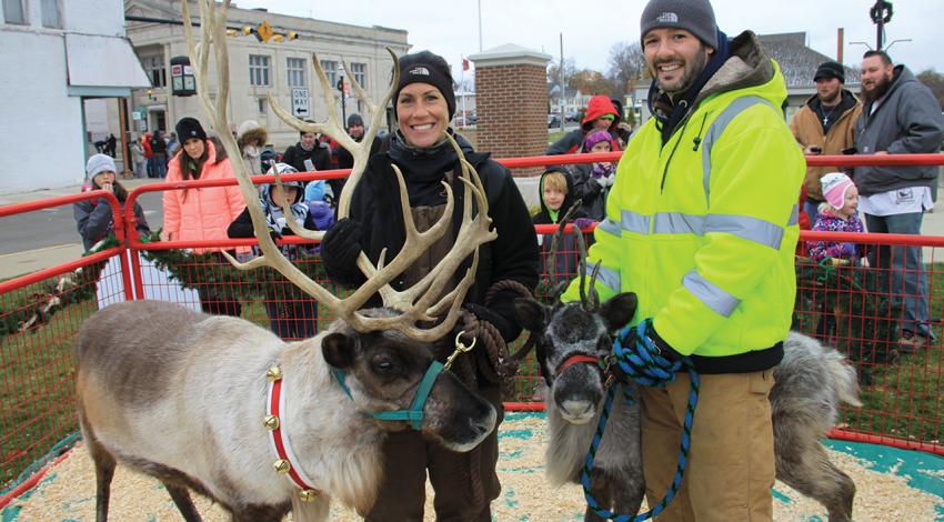 Nathan and Brienna Kleer smile with two reindeer.