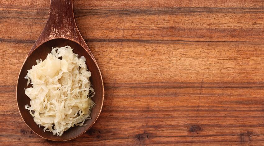 An image of sauerkraut on a wooden spoon.