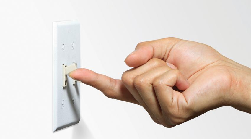 A hand flips on a light switch.