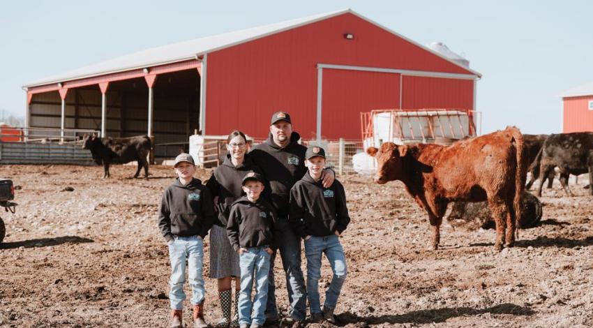 Co-op members posing in front of a pole barn built by the company their family owns and operates.