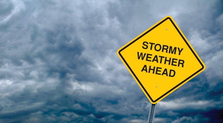 Stormy weather ahead sign in front of dark stormy sky background.