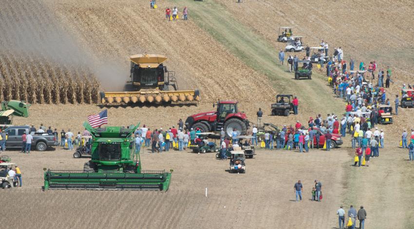 An overhead shot of tractors in a farm field surrounded by people