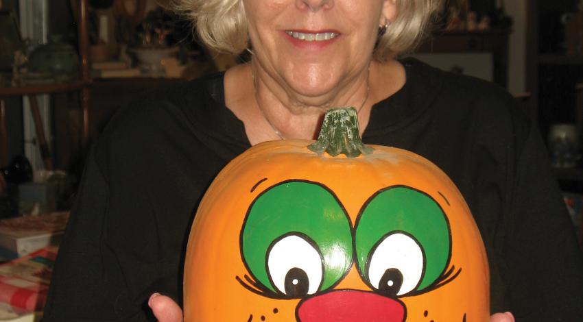 A woman holding a hand-painted pumpkin