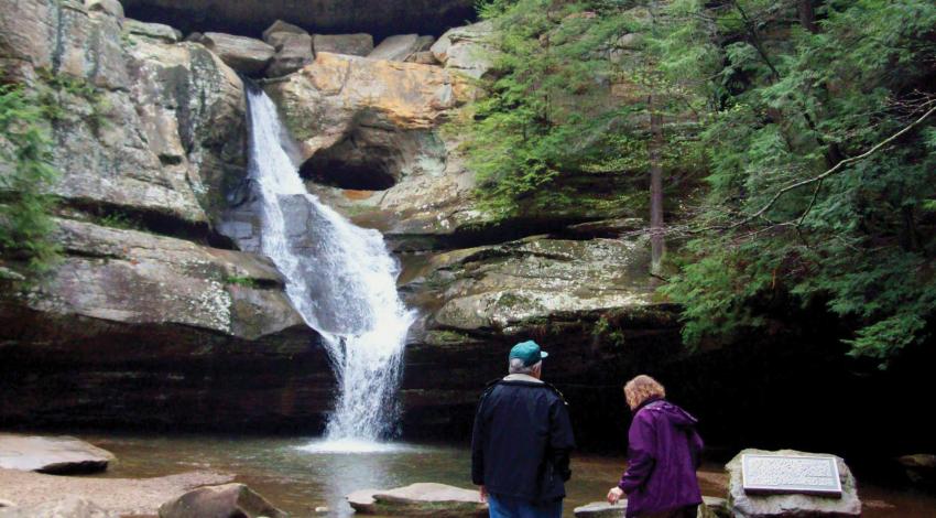 Inn & Spa at Cedar Falls is a 75-acre Hocking Hills resort. A couple looking at a waterfall in the woods
