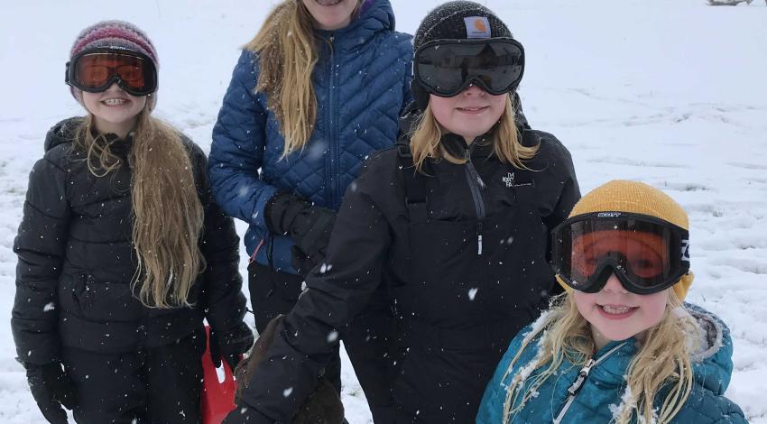Three girls and a dog in the snow