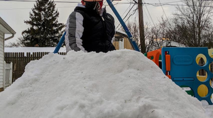 boy sitting on snow mound above tunnel