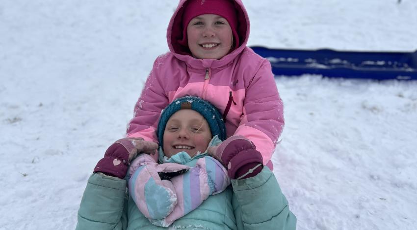 two girls on sled in snow