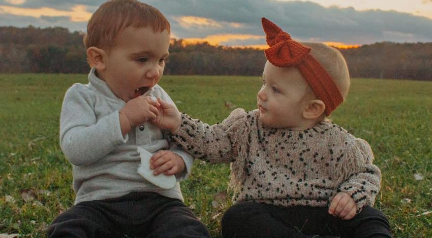 small child and baby sitting in grass