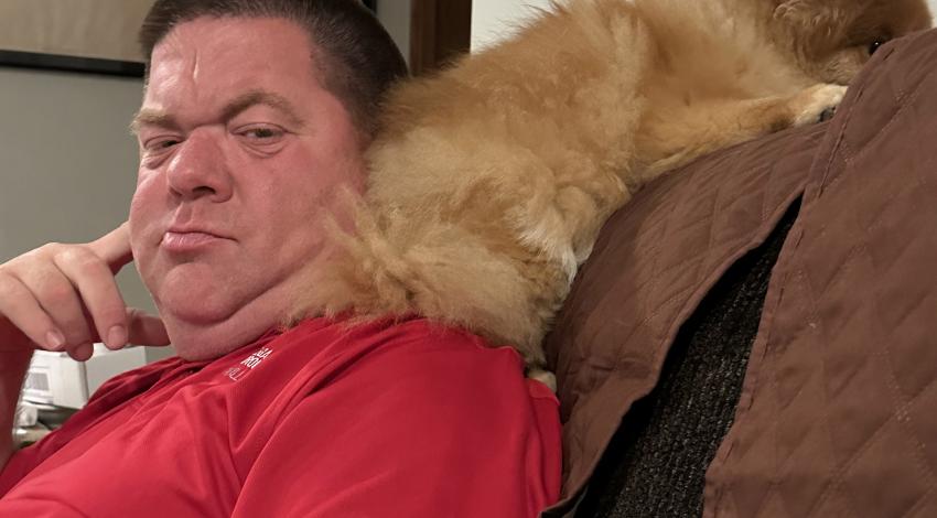 man on couch with dog on shoulder