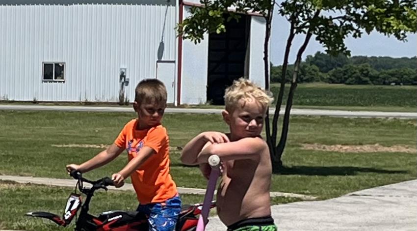 two kids - on one a bike and one on a scooter