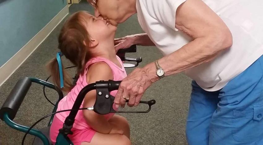 woman leaning down to kiss little girl