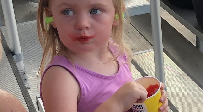 Little girl eating red shaved ice from a cup