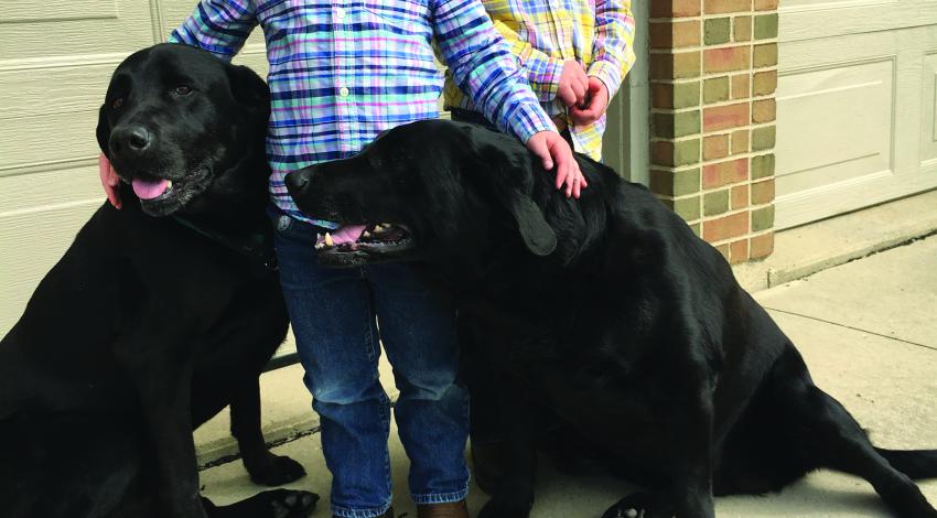 two boys with two black dogs