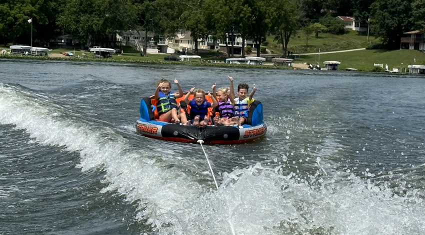 kids on a tube behind a boat