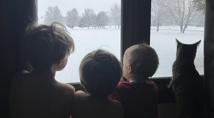 children and cat looking at snow through window