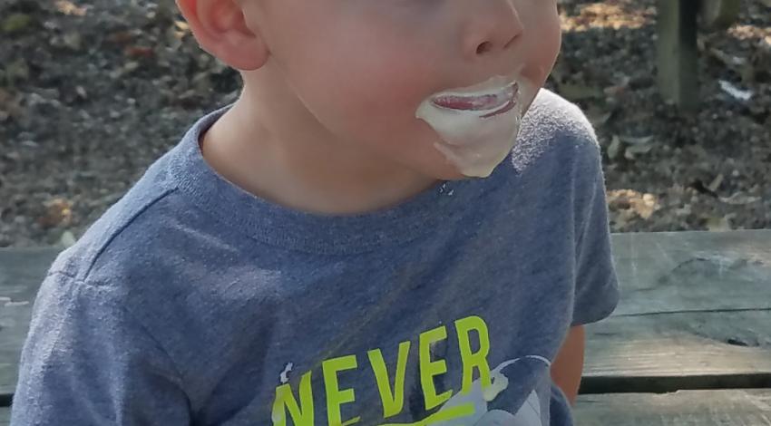 little boy with ice cream cone and ice cream on his face