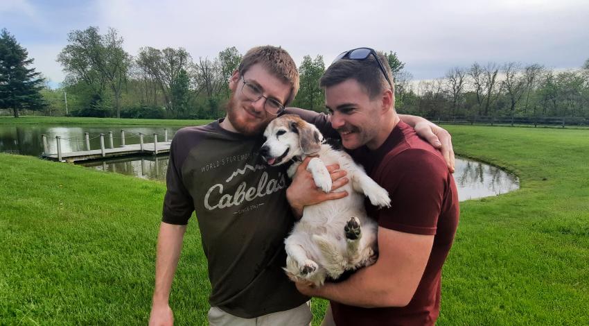 two young men holding a smiley dog