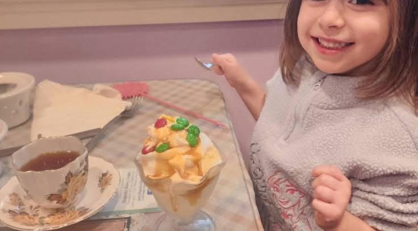 little girl having tea at table