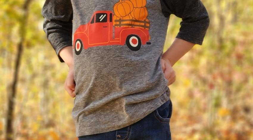 little boy standing in front of fall trees and leaves