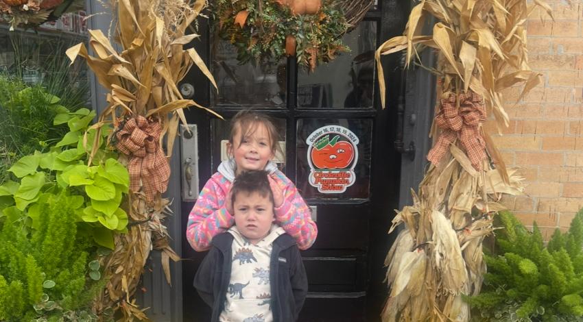 two children surrounded by autumn decorations