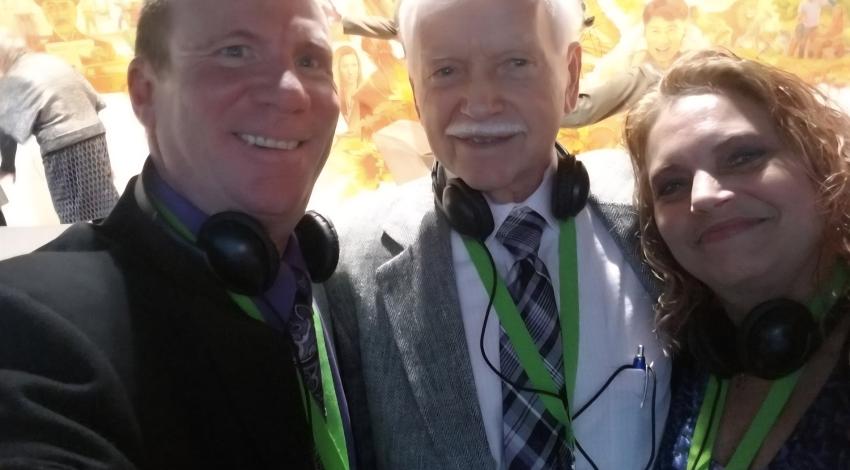 two men and a woman with headphones around their necks