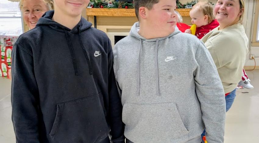 two boys photobombed by two women in back