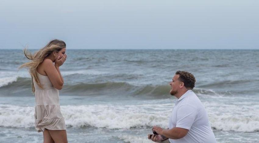 man on knee in front of woman on beach