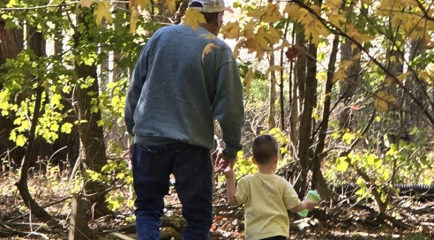 man and little boy walking by autumn trees