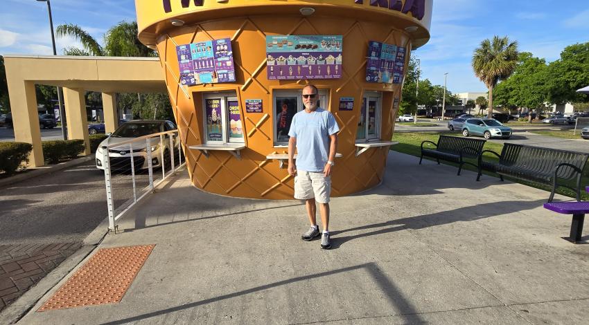 man standing in front of ice cream cone stand