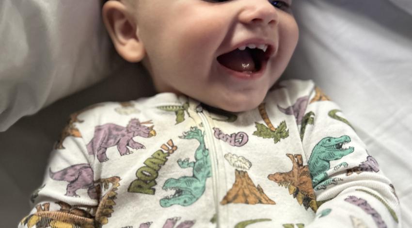 smiling baby in dinosaur pajamas