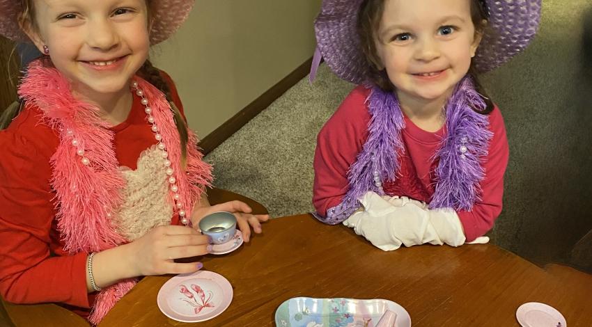 two little girls in hats having tea