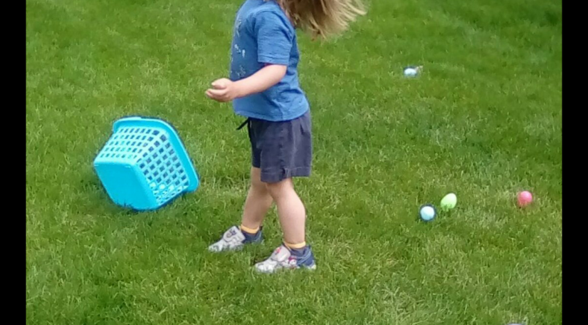 child in grass with Easter eggs