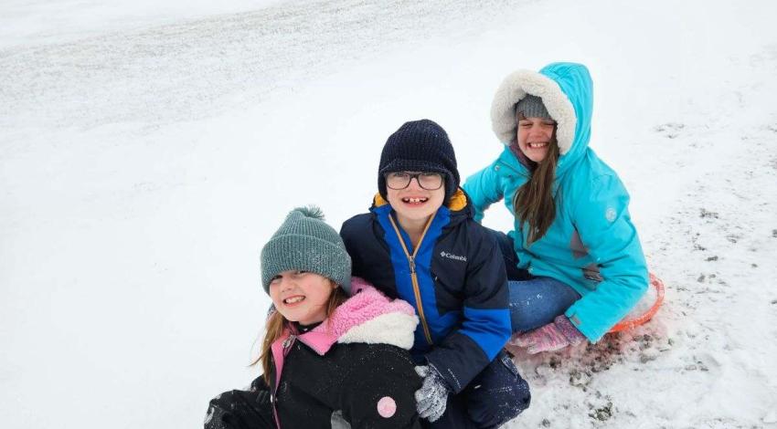 three kids on sled in snow