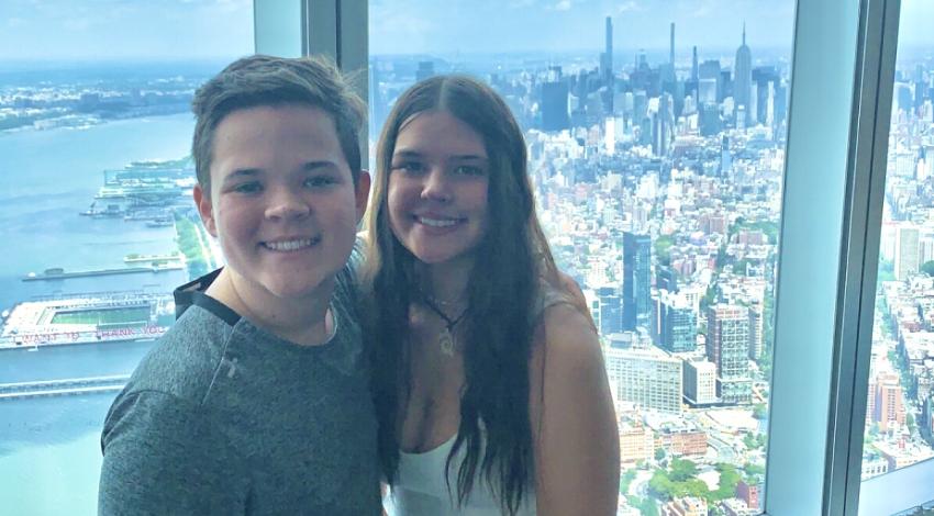 girl and boy in front of high window overlooking city