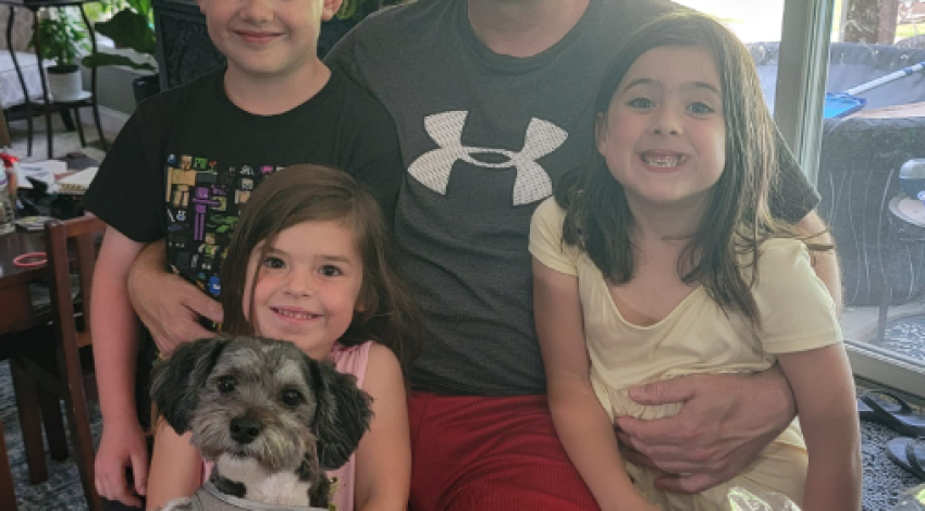 man and three children posing with dog
